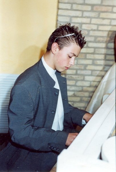 Al pianoforte, in giacca e cravatta