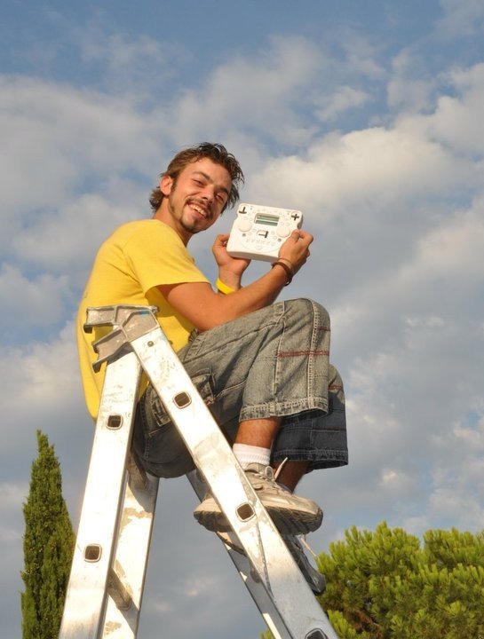 Damiano in cima a una scala davanti al palco mentre pilota la regia con un controller wireless